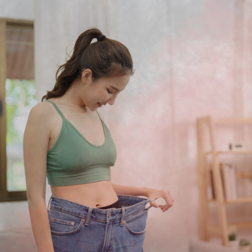 Person celebrating weight loss by fitting into looser jeans, representing the stages of noticing weight loss